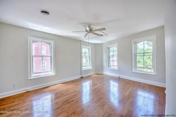a view of an empty room with wooden floor and a window