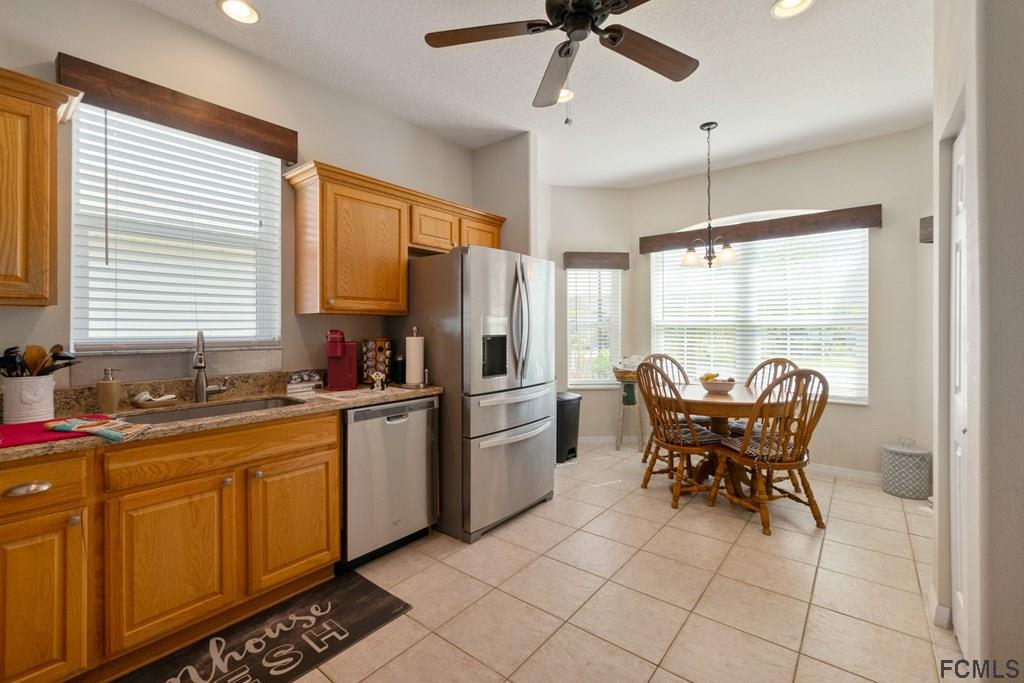 16 Raintree Circle Palm Coast, FL 32164 - Photo 19 of 45 a kitchen with stainless steel appliances granite countertop a stove a refrigerator a sink dishwasher a dining table and chairs with wooden floor
