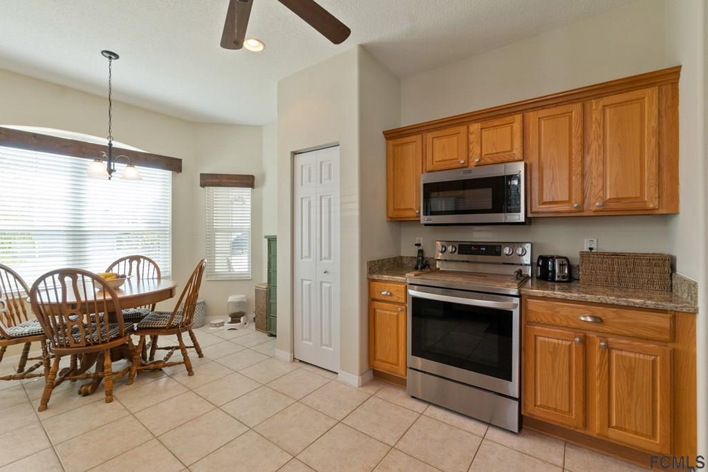 16 Raintree Circle Palm Coast, FL 32164 - Photo 20 of 45 a kitchen with stainless steel appliances granite countertop a stove top oven a sink a dining table and chairs