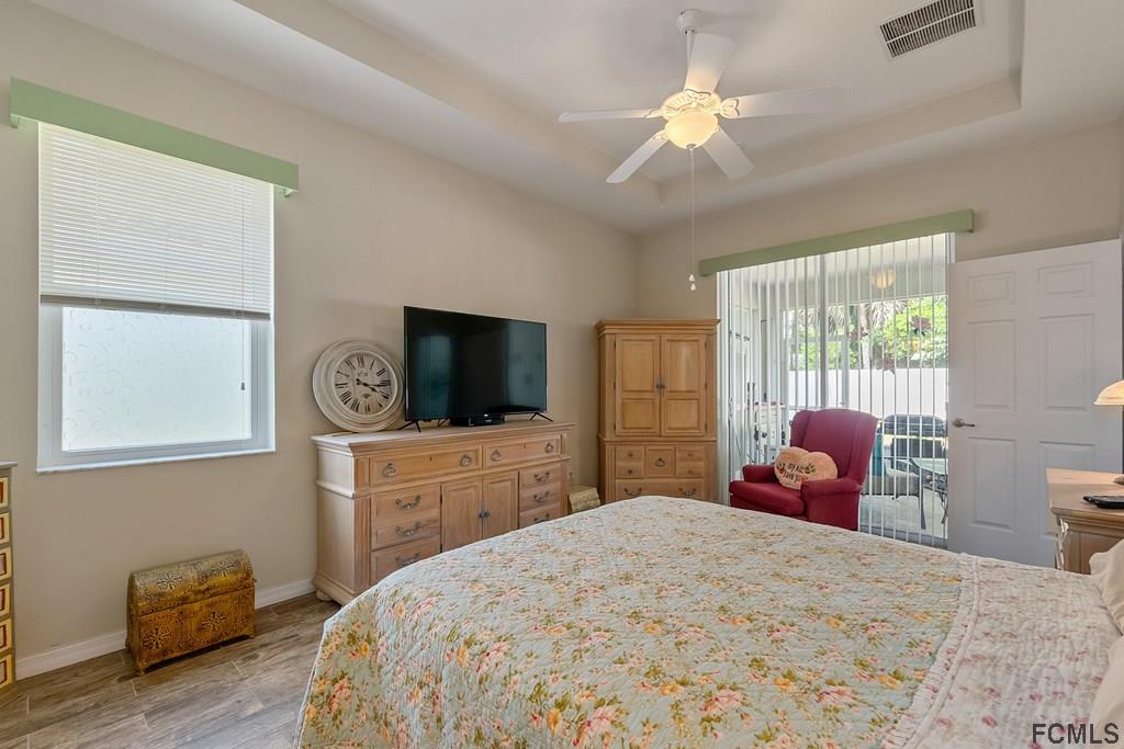16 Raintree Circle Palm Coast, FL 32164 - Photo 27 of 45 a bedroom with a bed a chandelier and a television