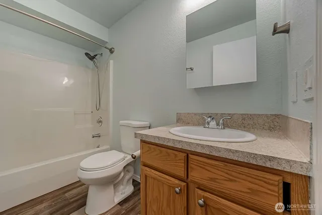 a bathroom with a granite countertop sink a toilet and shower