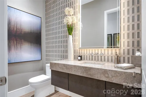 a bathroom with a granite countertop sink a toilet a mirror and shower