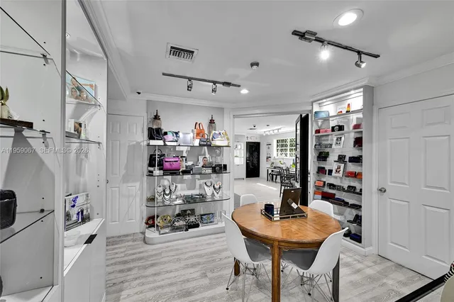 a room with stainless steel appliances kitchen island granite countertop a dining table chairs and a refrigerator