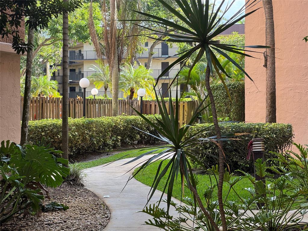 6800 Cypress Road, Unit 102 Plantation, FL 33317 - Photo 2 of 29 a view of yellow house with a yard and potted plants