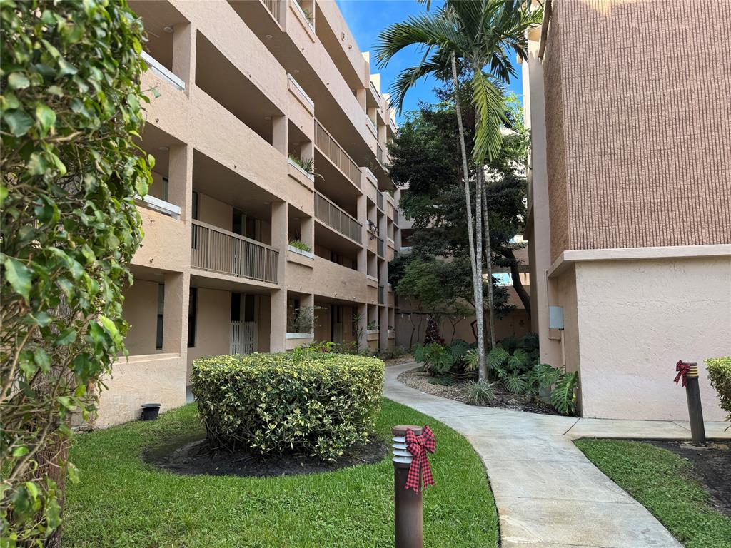6800 Cypress Road, Unit 102 Plantation, FL 33317 - Photo 26 of 29 a front view of a multi story residential apartment building with yard and green space