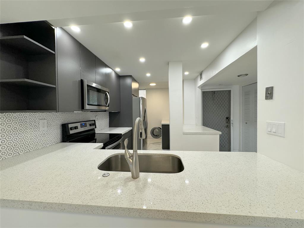 6800 Cypress Road, Unit 102 Plantation, FL 33317 - Photo 5 of 29 a large white kitchen with a large counter top stainless steel appliances and cabinets