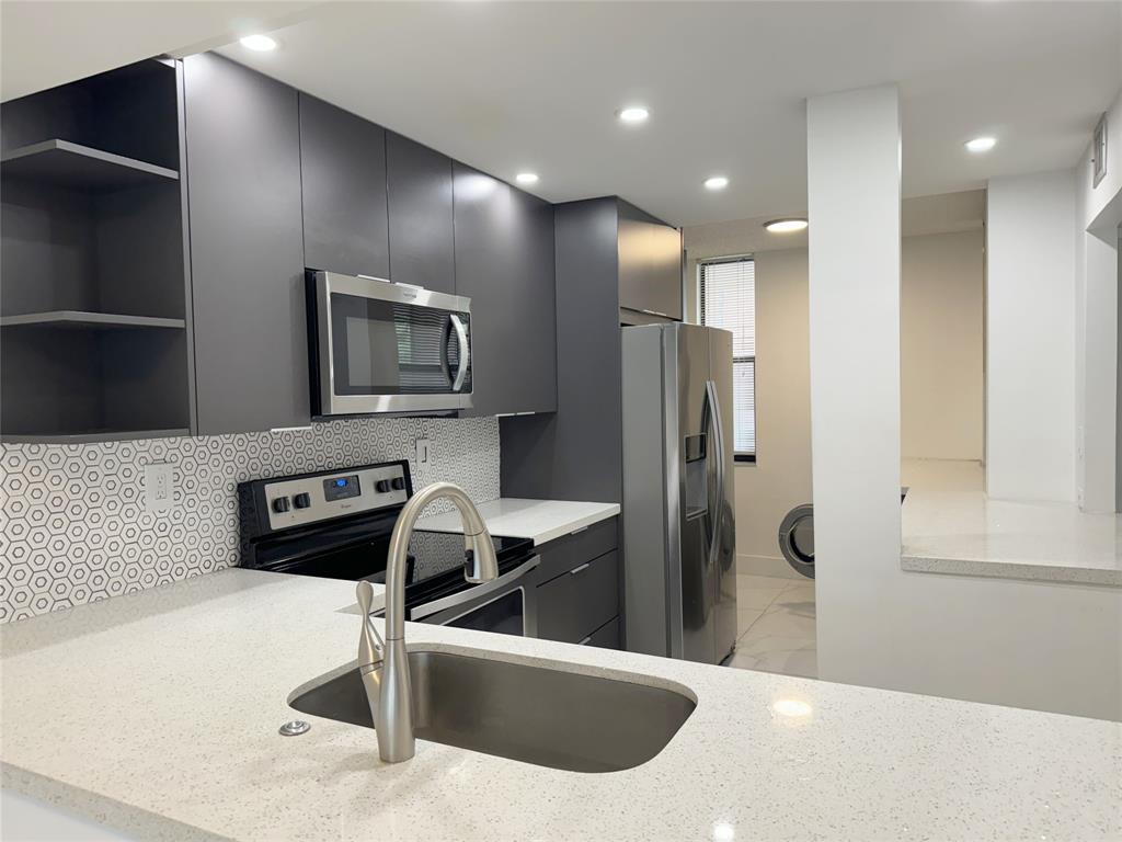 6800 Cypress Road, Unit 102 Plantation, FL 33317 - Photo 7 of 29 a kitchen with stainless steel appliances a microwave a stove and a refrigerator