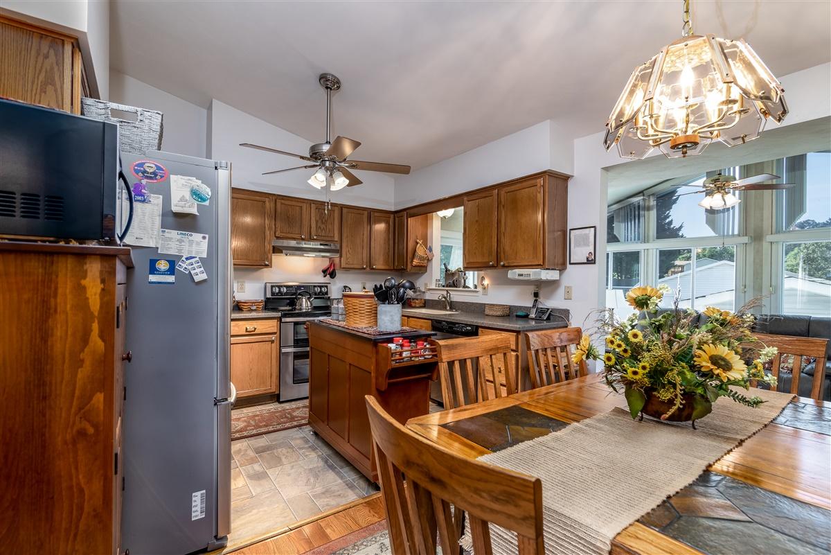 1849 Morgans Mill Road Goodview, VA 24095 - Photo 8 of 40 a kitchen with stainless steel appliances granite countertop a stove top oven a refrigerator a sink dishwasher a dining table and chairs with wooden floor
