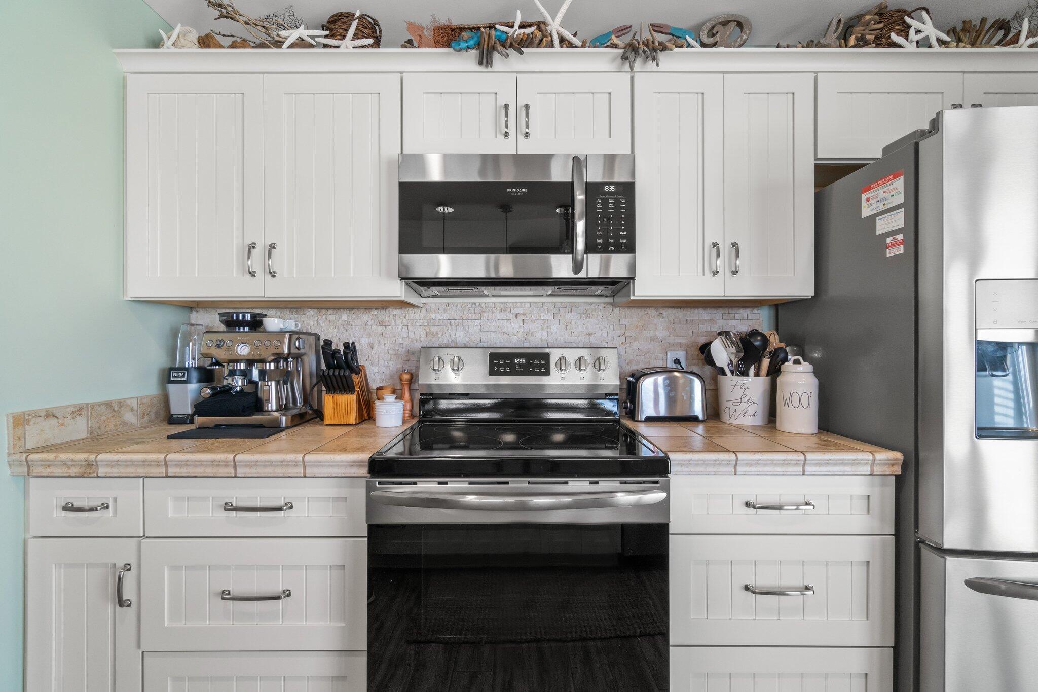15100 Front Beach Road, Unit 1302 Panama City Beach, FL 32413 - Photo 26 of 67 a kitchen with granite countertop white cabinets and stainless steel appliances