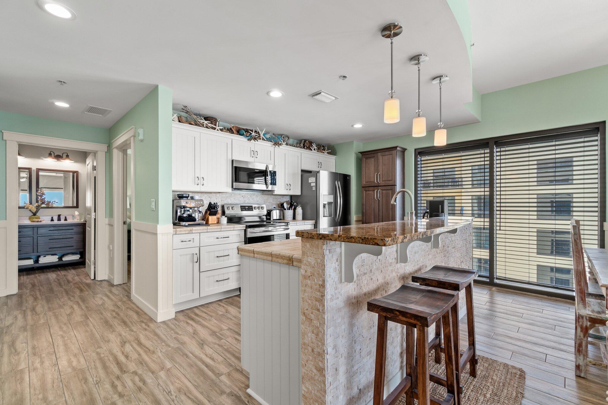 15100 Front Beach Road, Unit 1302 Panama City Beach, FL 32413 - Photo 27 of 67 a kitchen with stainless steel appliances kitchen island granite countertop a refrigerator a stove top oven a sink dishwasher and wooden cabinets with wooden floor
