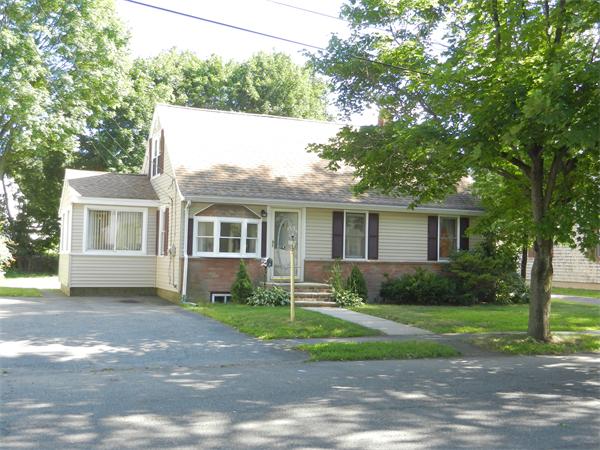 a front view of a house with a garden and trees