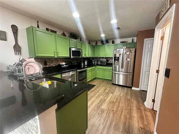 a kitchen with granite countertop a refrigerator a sink a stove and washer