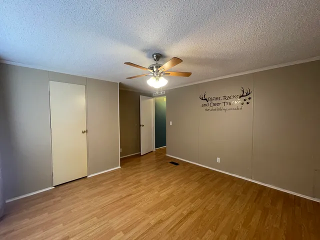 an empty room with wooden floor and a ceiling fan