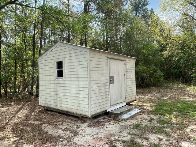 a view of a small white house with a small yard and large tree