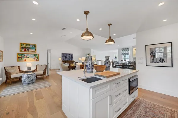 a kitchen with stainless steel appliances kitchen island granite countertop a sink and white cabinets with wooden floor