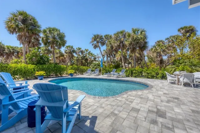 a view of backyard with seating space and trees in the background
