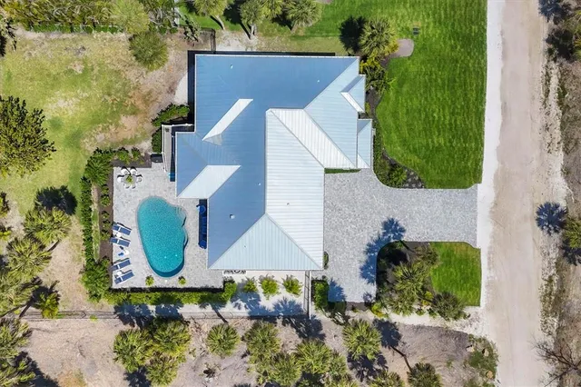an aerial view of a house with swimming pool and large trees