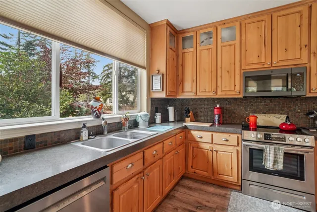 a kitchen with stainless steel appliances granite countertop a sink a stove top oven a counter space and cabinets