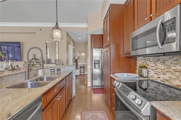 a kitchen with stainless steel appliances granite countertop a sink a stove and a wooden cabinets