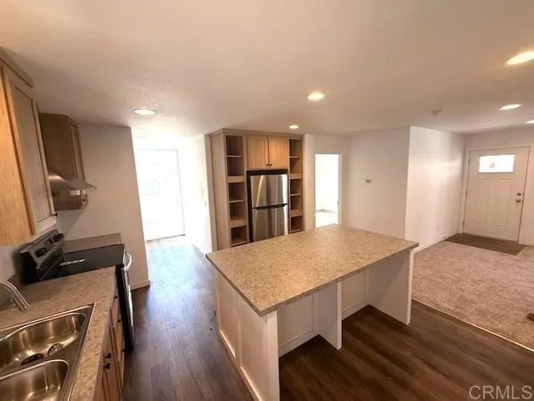 a open kitchen with kitchen island a stove and a wooden floors