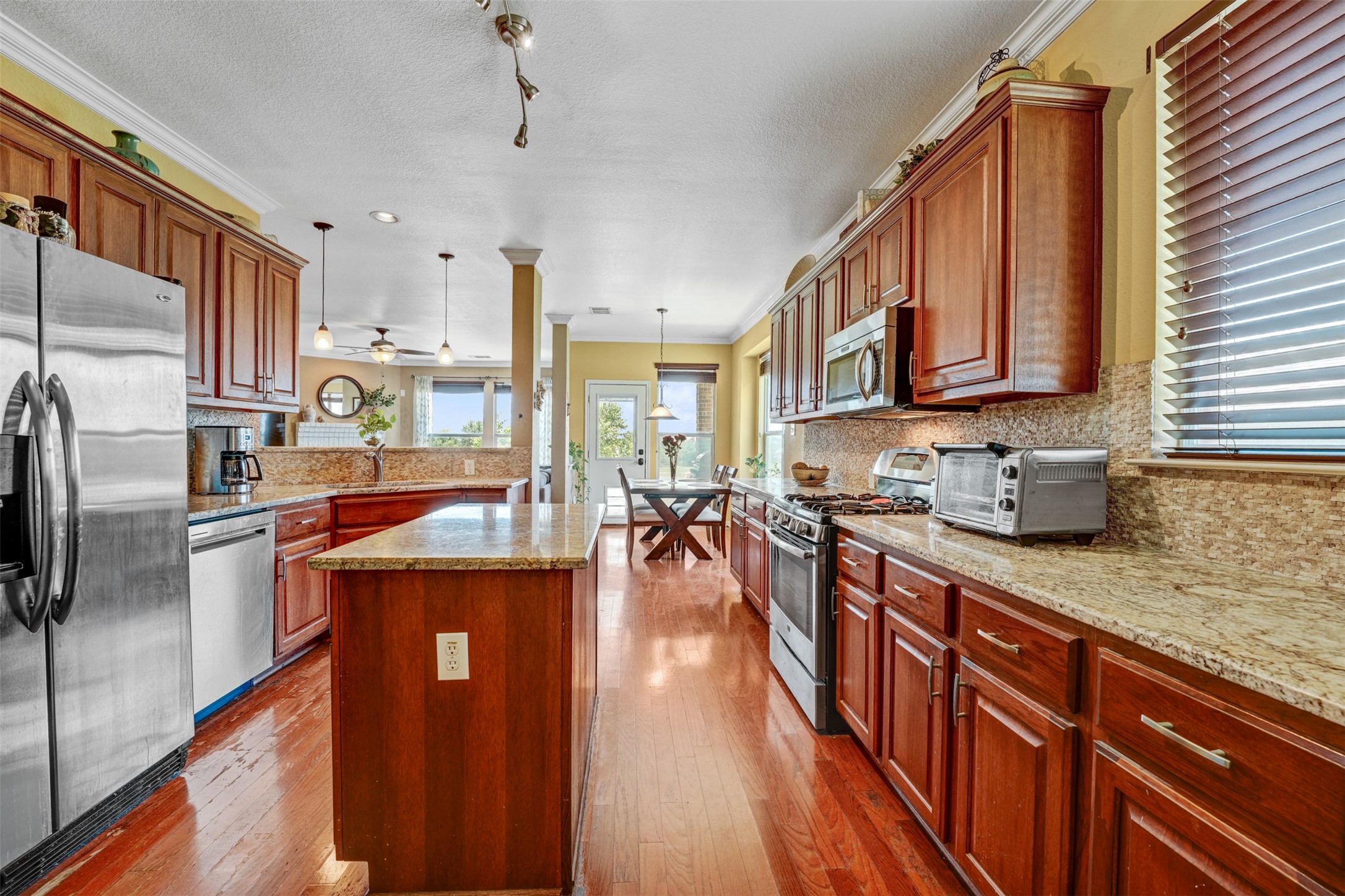 2521 Amen Corner Road Pflugerville, TX 78660 - Photo 10 of 40 Expansive kitchen featuring wood-finish flooring, granite countertops, and rich wood cabinetry