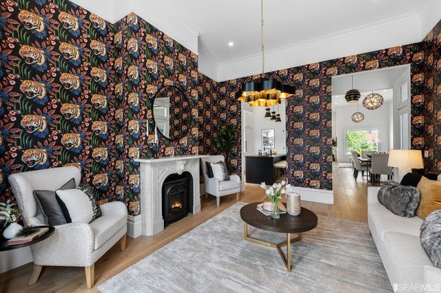 a view of a dining room and livingroom with furniture wooden floor a rug a flat screen tv a painting and a chandelier