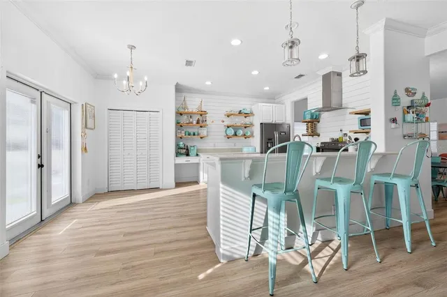 a view of a dining room and livingroom with furniture wooden floor kitchen chandelier