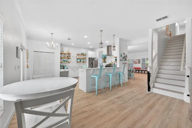 a room with stainless steel appliances kitchen island granite countertop a table chairs and a refrigerator