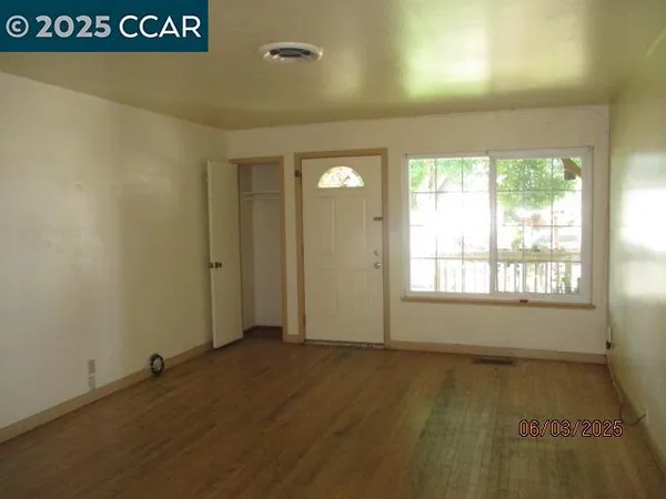 an empty room with wooden floor and windows