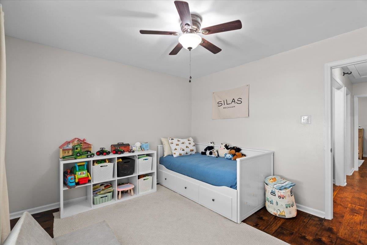 150 Liberty Road Moscow, TN 38057 - Photo 15 of 36 Light gray wall paint, dark wood-finish flooring, white trim, ceiling fan with light fixture, and an open doorway leading to a hallway