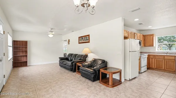 a living room with furniture a chandelier and kitchen view