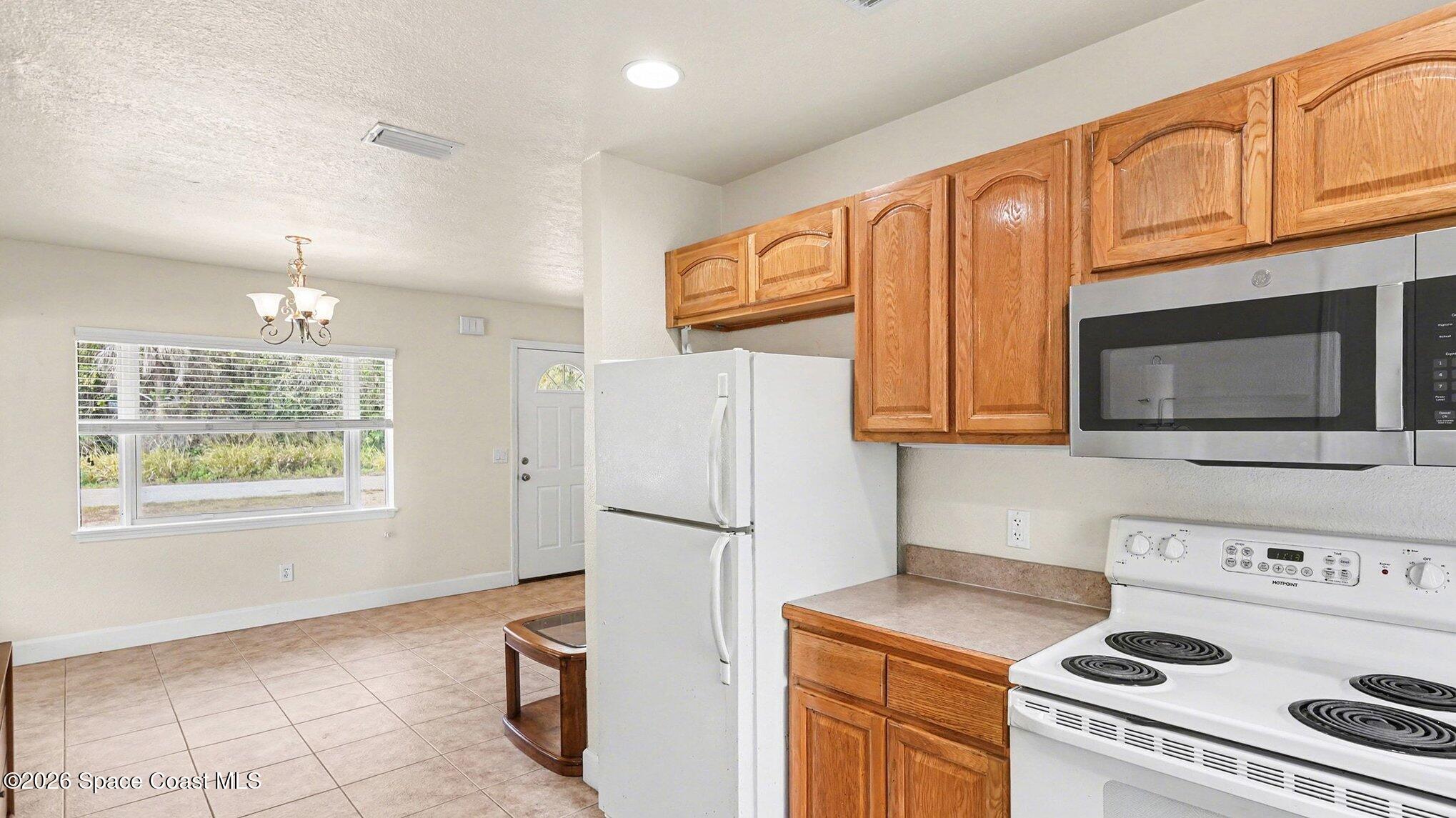 136 Gray Road Melbourne, FL 32904 - Photo 10 of 27 a kitchen with stainless steel appliances granite countertop a refrigerator a stove a sink and a microwave