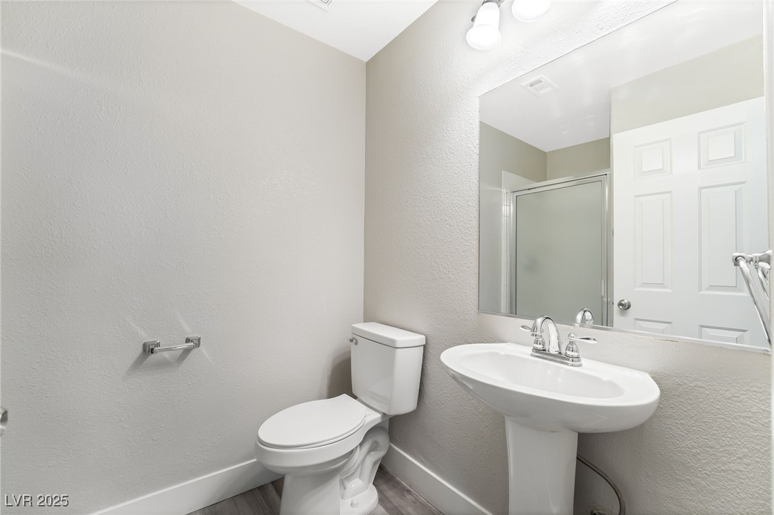1533 Sabatini Drive Henderson, NV 89052 - Photo 10 of 27 Bathroom with a textured wall, a shower stall, and wood finished floors