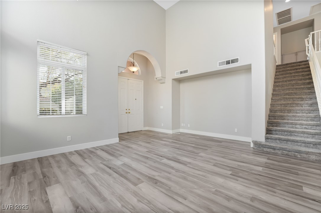 1533 Sabatini Drive Henderson, NV 89052 - Photo 2 of 27 Unfurnished living room with a high ceiling, stairway, light wood-type flooring, and arched walkways