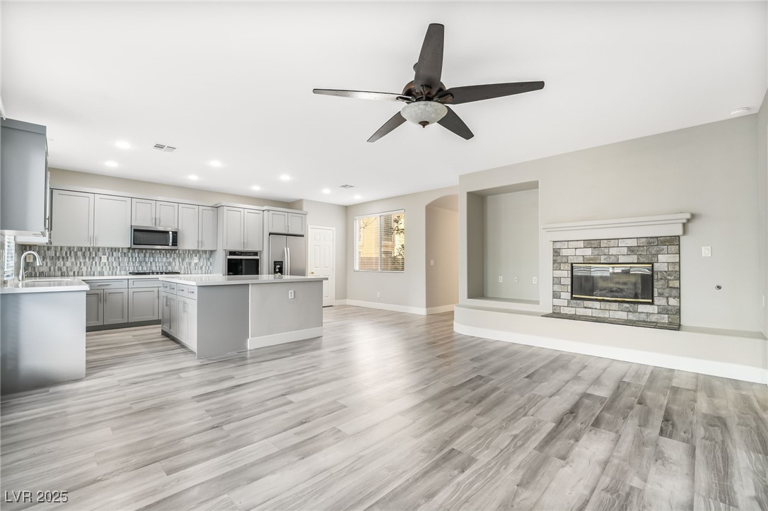 1533 Sabatini Drive Henderson, NV 89052 - Photo 27 of 27 Kitchen with gray cabinets, a brick fireplace, open floor plan, light wood-type flooring, and stainless steel appliances