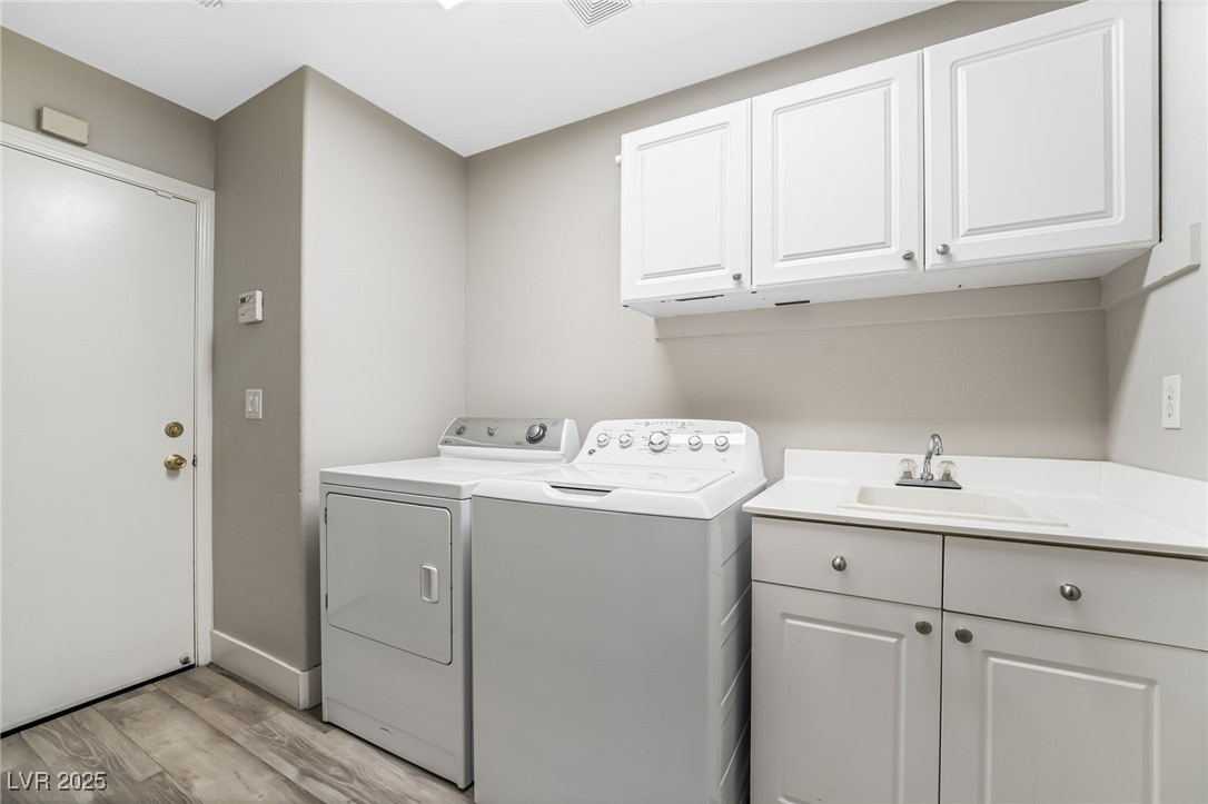1533 Sabatini Drive Henderson, NV 89052 - Photo 9 of 27 Laundry area featuring independent washer and dryer, light wood-style floors, and cabinet space