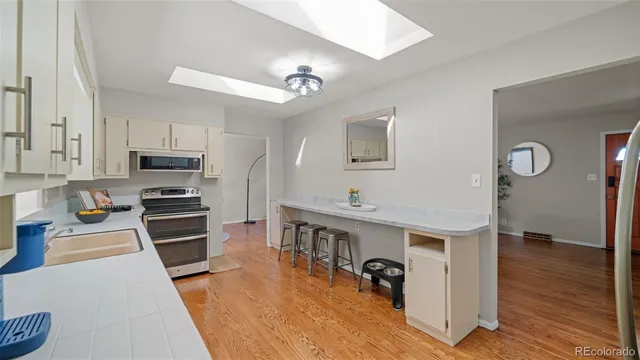 a kitchen with stainless steel appliances granite countertop a refrigerator a stove oven a sink dishwasher and white cabinets with wooden floor