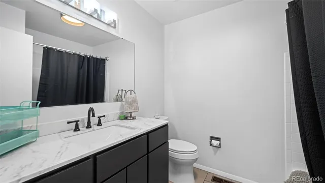 a bathroom with a granite countertop sink a toilet and a mirror
