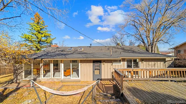 a view of a house with a wooden deck and a lounge chair