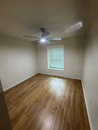 an empty room with wooden floor chandelier and windows