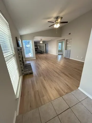 a view of an empty room with window and wooden floor