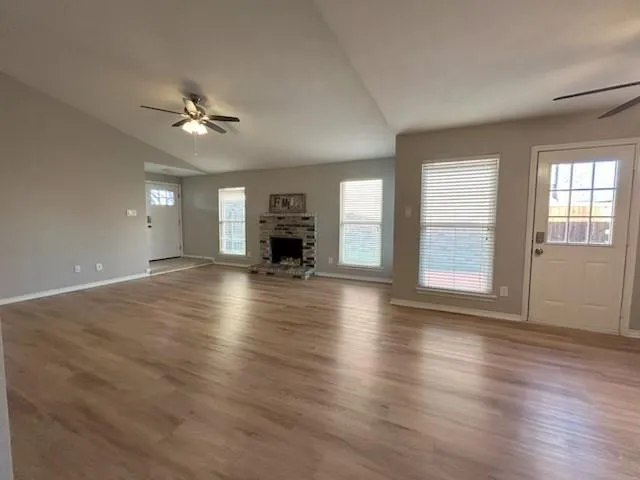 a view of an empty room with window and wooden floor