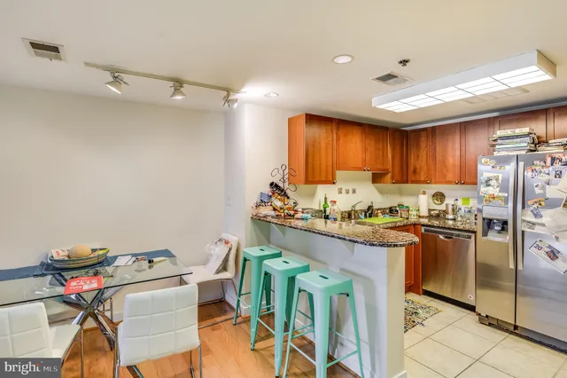 a kitchen with granite countertop a table chairs refrigerator and microwave