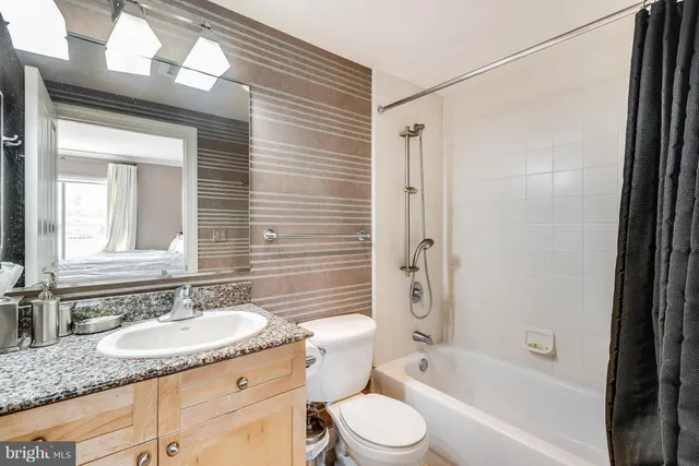 a bathroom with a granite countertop sink toilet and shower
