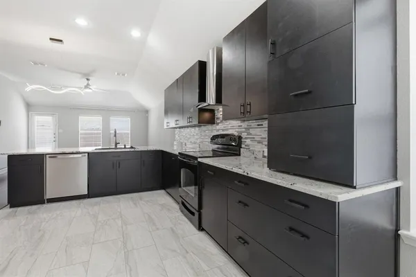 a large kitchen with stainless steel appliances kitchen island granite countertop a refrigerator and a sink