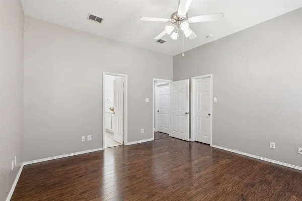 an empty room with wooden floor and ceiling fan