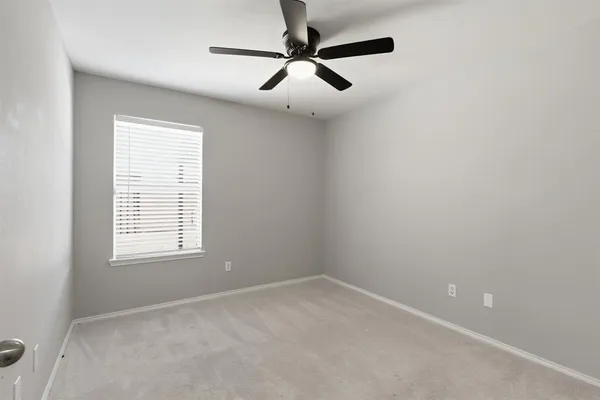 an empty room with a window and a fan