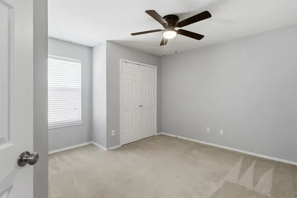 an empty room with a window and a fan