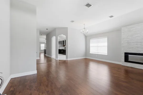 a view of an empty room with window and wooden floor