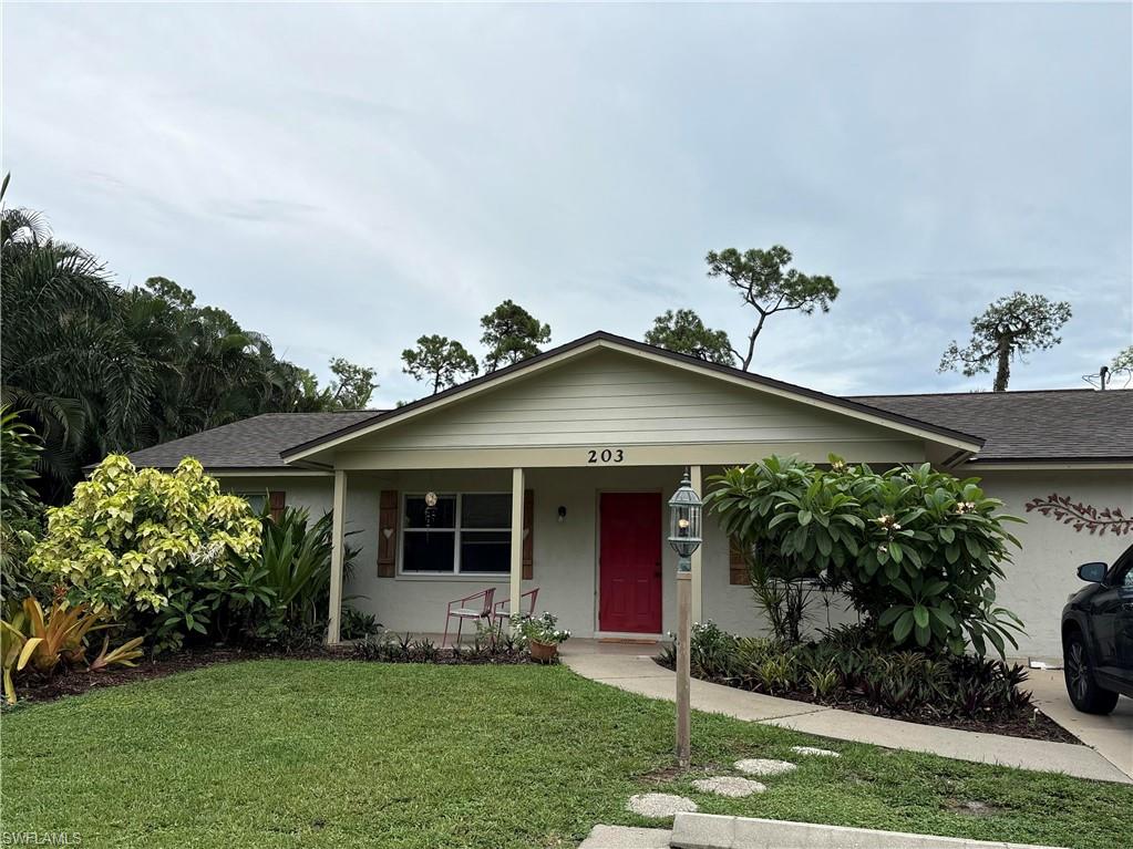 203 Esther Street Naples, FL 34104 - Photo 13 of 33 Ranch-style home featuring a front yard, a porch, a shingled roof, and stucco siding